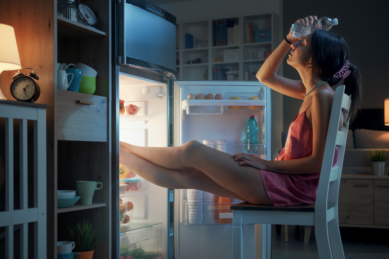 donna con i piedi nel frigorifero a causa del caldo