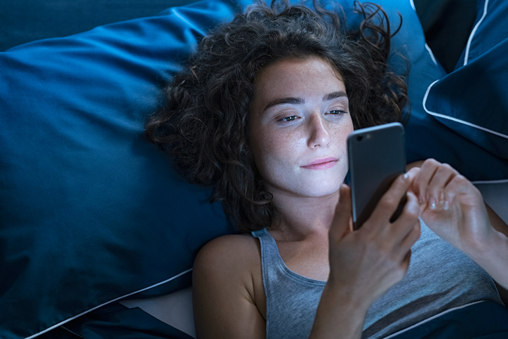 Ragazza guarda il telefonino a letto