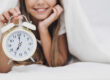 Ritmo-circadiano immagine di una ragazza sotto le coperte con in mano una sveglia